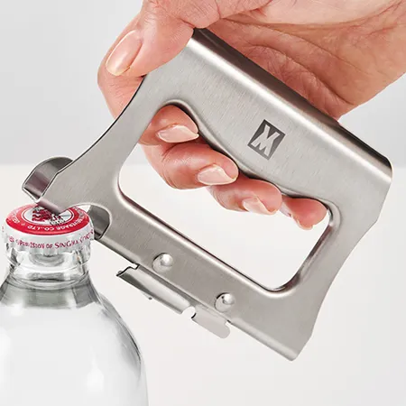 Hand using a Wagensteiger stainless steel opener on a crown-cap bottle